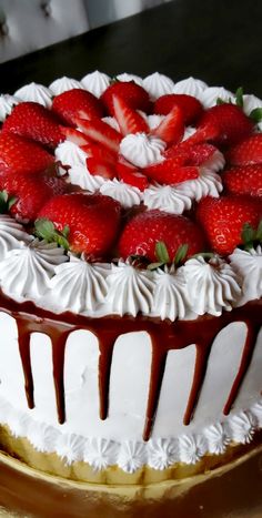 a chocolate covered cake with strawberries on top and drizzled in icing