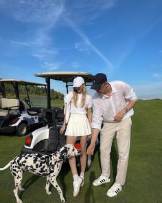 a man and woman standing next to a black and white dalmatian on a golf course