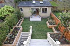 a small backyard garden with steps leading to the back door and stairs up to the roof