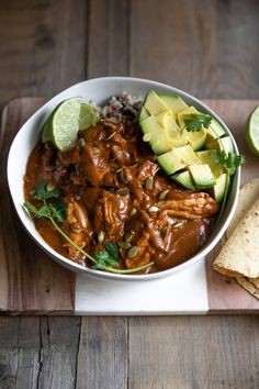 a bowl filled with meat and vegetables next to tortilla chips on a cutting board