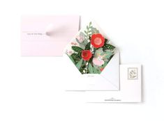 two envelopes with flowers on them are next to a postcard that has a postage stamp