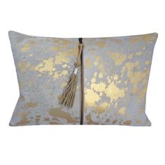 a gold and silver pillow with tassels on it