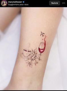 a woman's foot with a wine glass and flower tattoo on it