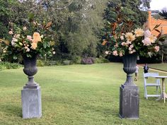 two large vases with flowers are in the grass