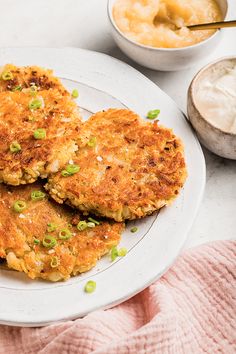 two crab cakes on a white plate next to some dipping sauce and a pink towel