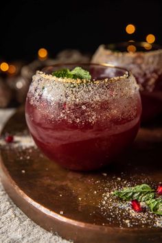 two glasses filled with liquid and topped with sprinkles on a wooden platter