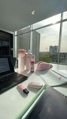 an open laptop computer sitting on top of a white desk next to a pink pillow