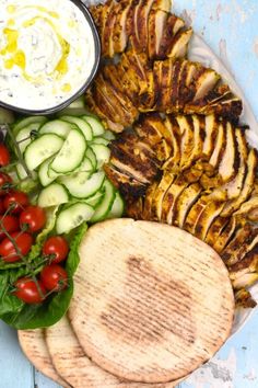 a plate with grilled chicken, cucumbers, tomatoes, and other vegetables