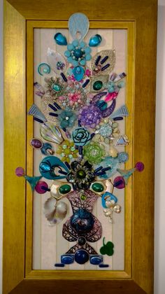 a wooden frame holding a glass vase filled with lots of different colored beads and jewels