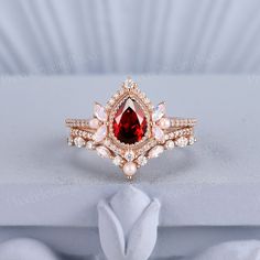 a red and white ring sitting on top of a piece of cloth next to a flower