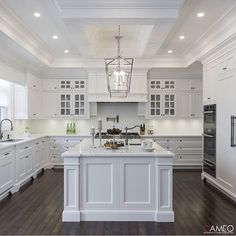 a large kitchen with white cabinets and an island in the middle of the room is lit by pendant lights