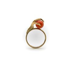 This is part of Chairish’s Fine Jewelry assortment.  In this 18k gold vintage ring, a three-dimensional claw rises up and clasps a coral bead. The claw is impressively lifelike, with a matte texture and intricate detail. The bead is beautiful salmon colored coral that pops against the matte gold surface. The clever design of the ring—which holds the bead securely on a bar through its center—allows the bead to spin, creating the sense that this ring has mystical powers.   The ring is marked 750. Elegant Brass Rings With Cabochon, Elegant Carnelian Yellow Gold Rings, Elegant Carnelian Ring In Yellow Gold, Elegant Yellow Gold Carnelian Ring, Elegant Yellow Gold Jewelry With Red Coral, Formal Yellow Gold Jewelry With Red Coral, Red Coral Ring, Gold Vintage Ring, Green Cocktail