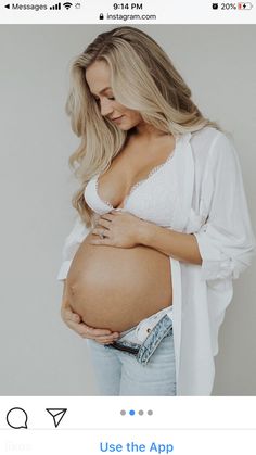 a pregnant woman in white shirt and jeans posing with her belly exposed to the side