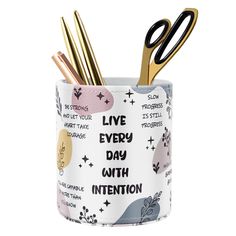 a pen holder with scissors in it and writing on the side that says live every day with intention