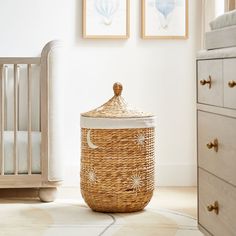 a wicker basket sitting on the floor next to a baby's crib