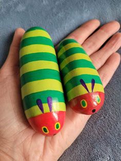 two painted rocks in the shape of caterpillars on someone's hand