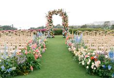 an outdoor ceremony setup with rows of chairs and flowers on the grass in front of them