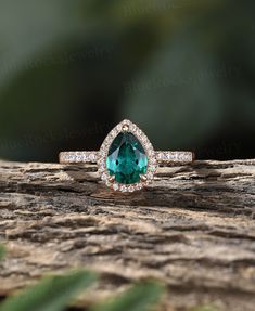 an oval cut green tourmaline surrounded by white diamonds on a piece of wood