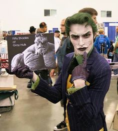 a man dressed as the joker holding up a book