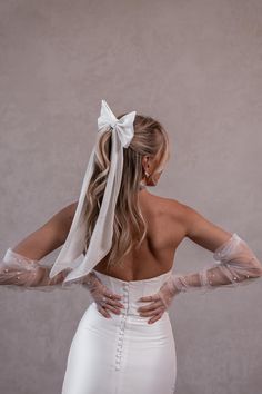 a woman with her back to the camera, wearing a white dress and long gloves