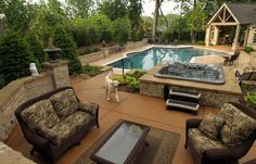 a dog standing in front of a swimming pool surrounded by patio furniture and landscaping items