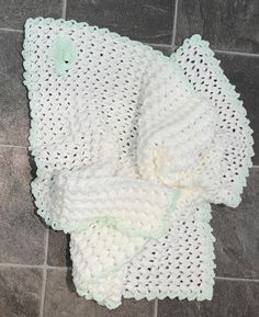 a white crocheted blanket laying on top of a tile floor