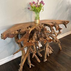 a table made out of driftwood with flowers in a vase on the top and bottom