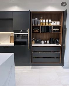 a kitchen with black cabinets and white tile flooring is shown in this image, there are many items on the shelves