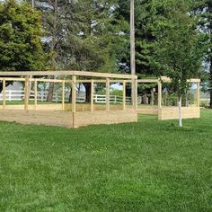 a wooden structure sitting on top of a lush green field