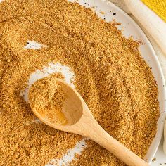 a wooden spoon in a white bowl filled with ground spices next to a yellow towel