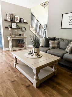 a living room with a couch, coffee table and stairs in the backround