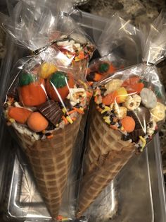 two ice cream cones with candy and candies on them in plastic wrapper bags