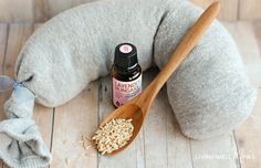 a wooden spoon sitting on top of a pillow next to a bottle of essential oils