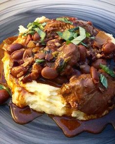 a blue plate topped with mashed potatoes and meat covered in sauce on top of it