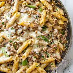 a skillet filled with pasta and meat covered in cheese