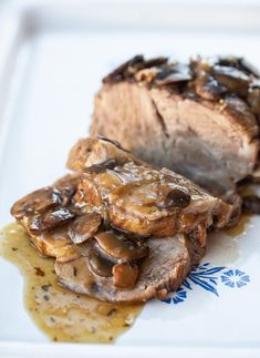 a white plate topped with meat covered in mushrooms