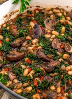 a pan filled with mushrooms, spinach and red peppers on top of a table