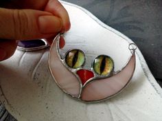 a person is holding a glass brooch with two eyes on it