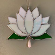 a white and green stained glass flower hanging from a hook on a wall in a room