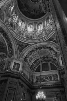 black and white photograph of the ceiling in an ornately decorated building with chandeliers