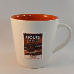 a white and orange coffee cup sitting on top of a table