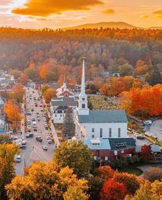 an aerial view of a small town in the fall with colorful trees and foliage surrounding it