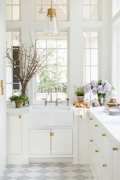 a white kitchen with checkered flooring and gold hardware on the cabinet doors is pictured in this image