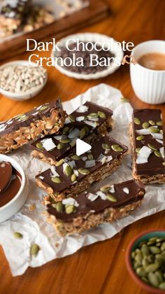 dark chocolate granola bar with nuts and seeds on the table next to cups of coffee