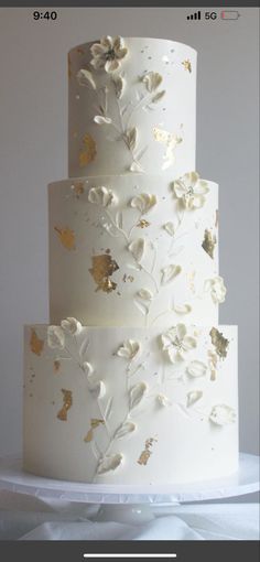 a white wedding cake with gold leaf decorations