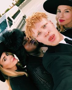 three people taking a selfie in front of a car