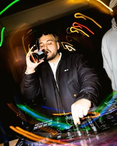 a man that is sitting at a dj's desk with some lights in the background