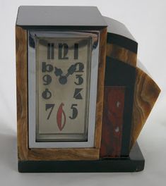 an old clock is sitting on a white surface with red and black pieces around it