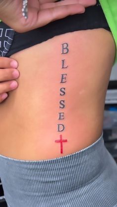 a woman with a cross tattoo on her back that says, blessing and the word below it