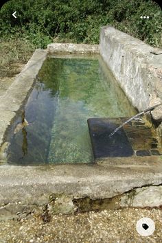 the water is running out of the hole in the stone wall and into the pond